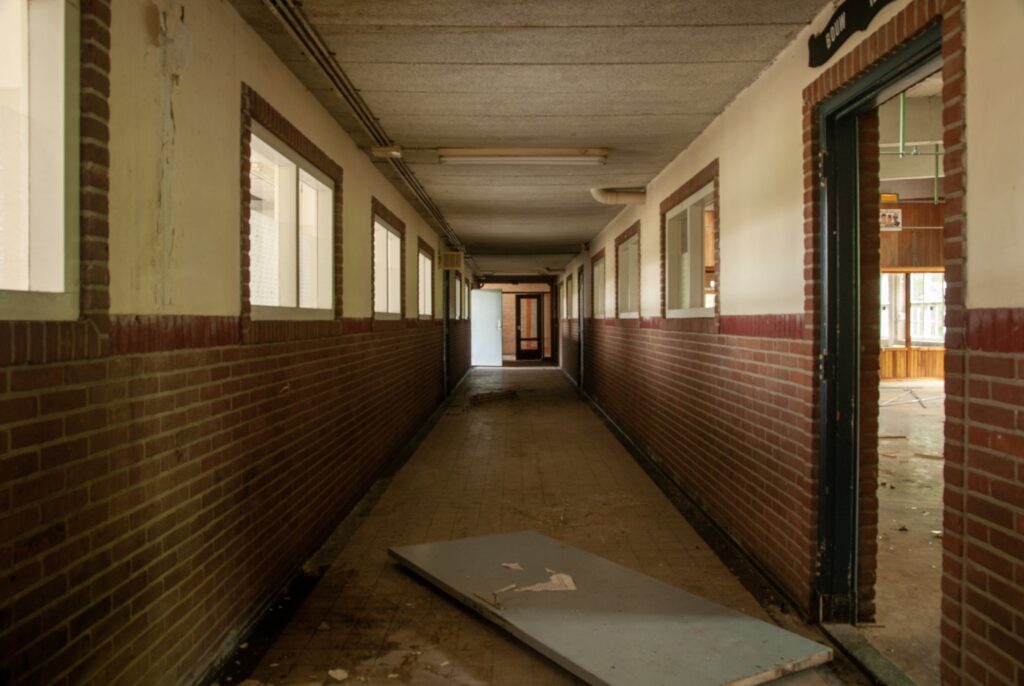 Interior shot of an empty hall of an abandoned school with broken doors